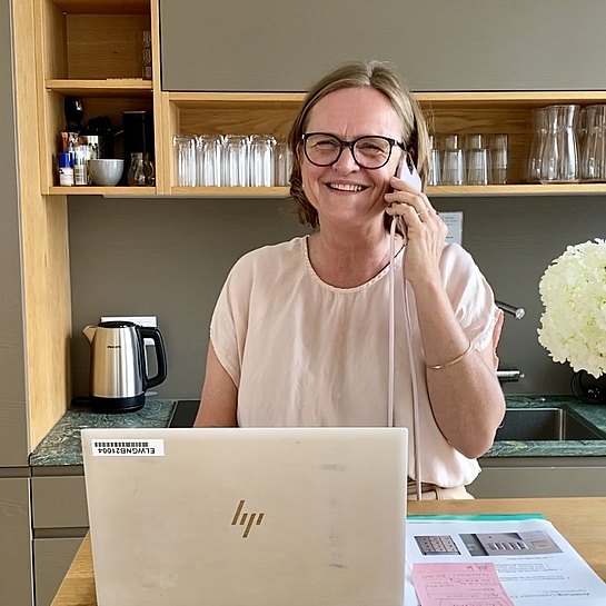 Frau telefoniert, lacht dabei in die Kamera