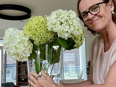 weibliche Person stellt große Blumenvase auf einem Tisch ab